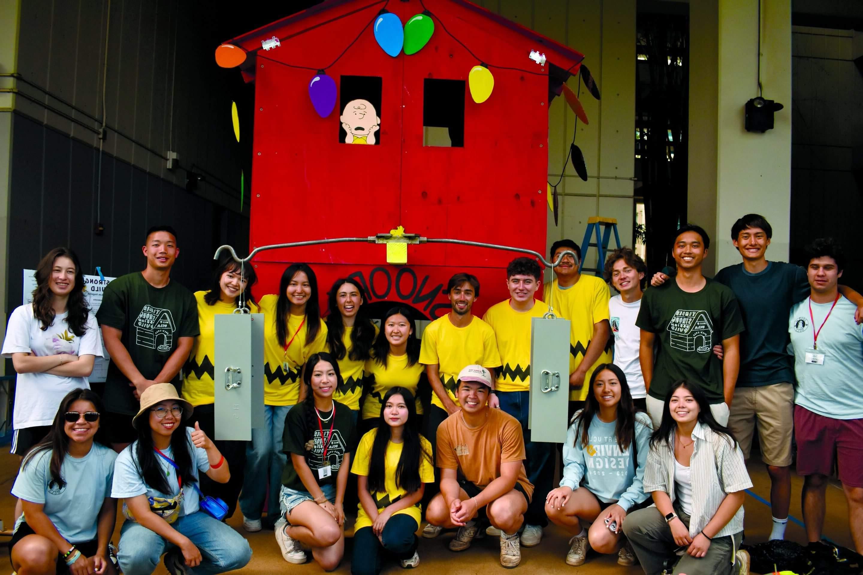 Proud students stand with their assembled tiny home decorated in a Snoopy motif.